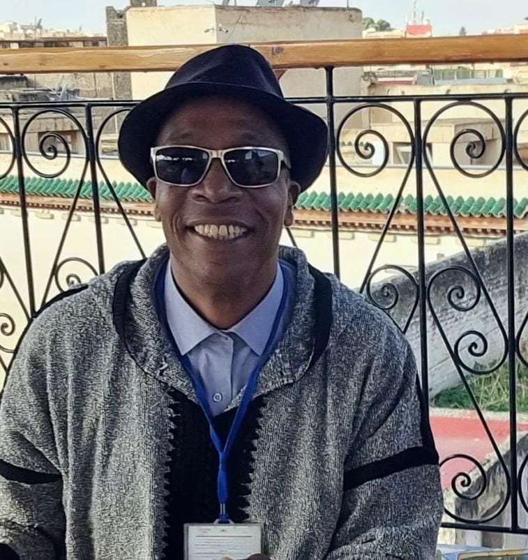 Driss in casual attire with traditional Moroccan architecture